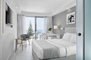 a white bedroom with a bed and a desk and a chair at Lichnos Beach in Parga +91 photos