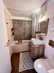 a bathroom with a tub and a sink and a toilet at BALI HOME Stylische Wohnung mit Terrasse in Schönefeld