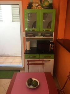 - une cuisine avec une table et une assiette de fruits dans l'établissement La maisonnette Ti-bou, à Petit-Bourg