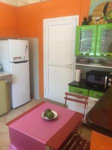 - une cuisine avec une table rose et un bol de fruits dans l'établissement La maisonnette Ti-bou, à Petit-Bourg