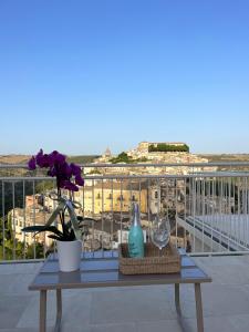 uma mesa com flores e copos de vinho numa varanda em La casa di Irene - Suites con vista em Ragusa