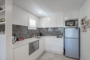 uma cozinha com armários brancos e um frigorífico em Luxury in the Heart of Hastings street 628 em Noosa Heads