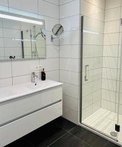 a white bathroom with a shower and a sink at Route du Circuit 23 in Stavelot
