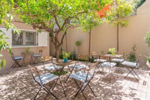 eine Terrasse mit Tischen und Stühlen unter einem Baum in der Unterkunft The Koukaki Residence in Athen