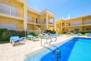 a villa with a swimming pool and blue chairs at Benjamin Apartment in Guia