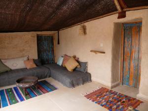a room with a bed and a couch and a table at Berber Beldi Camp in Imsouane