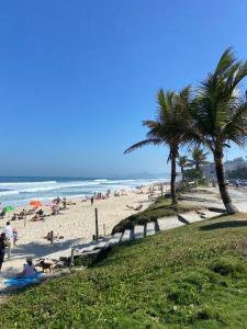 pessoas em uma praia com palmeiras e o oceano em Apartamento renovado Barra Bella no Rio de Janeiro