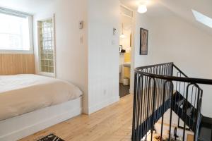 a white bedroom with a bed and a staircase at Le Central par Maison Dudley in Lac-Mégantic