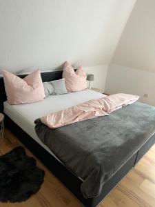 ein Bett mit rosa Kissen darüber in der Unterkunft Ferienwohnung Lütetsburg in Lütetsburg