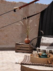 a patio with a vase and a chair and a table at Berber Beldi Camp in Imsouane