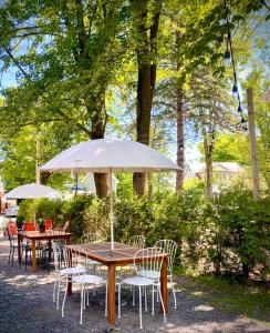 a wooden table with chairs and an umbrella at Le Central par Maison Dudley in Lac-Mégantic