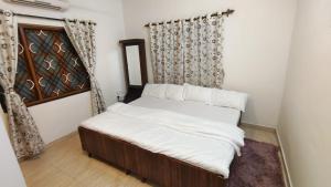 坎多林的住宿－Private 2bhk villa with kitchen Candolim-calangute Goa CW01，一间卧室配有一张带白色床单的床和一扇窗户。
