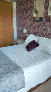 a large white bed with a purple pillow on it at Apartamento Mirador de Padin in Ribeira