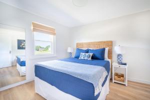 a white bedroom with a blue bed and a window at Marina Bay Cottages in Waterford