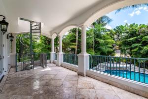 um alpendre com vista para uma piscina e árvores em Incredible 9 Bedroom 11 Bath Idlewyld Mansion em Fort Lauderdale