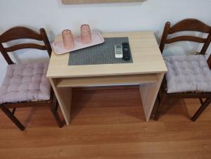 a wooden table with two chairs and a remote control at Soba Ivanka Nikšić in Karlobag