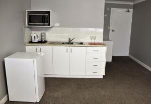 a white kitchen with a sink and a microwave at Bribie Island Square in Bongaree