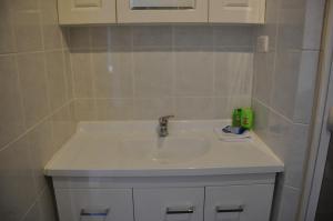 a white sink in a bathroom with white cabinets at Bribie Island Square in Bongaree