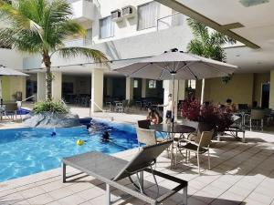 einen Pool mit einem Tisch, Stühlen und einem Sonnenschirm in der Unterkunft Flat Pertinho do Hot Park (200m)! Aconchegante! in Rio Quente