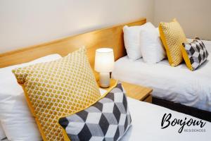 ein Schlafzimmer mit 2 Betten mit Kissen und einer Lampe in der Unterkunft Montmartre Suite - New Town 3BR-3BA Main Door - Free Parking & Patio by Bonjour Residences Edinburgh in Edinburgh