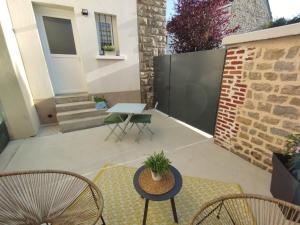 a patio with chairs and a table and a brick wall at La suite d'Arches in Charleville-Mézières