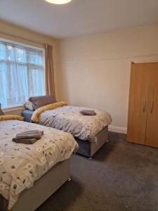 a bedroom with two beds and a cabinet and a window at Modern 3BD London Flat in London