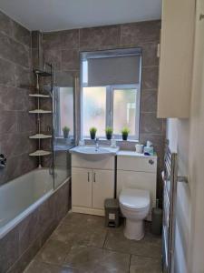 a bathroom with a sink and a toilet and a window at Modern 3BD London Flat in London