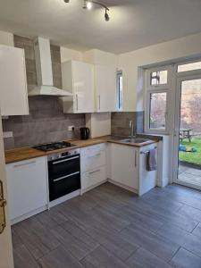 eine Küche mit weißen Schränken und einem Herd mit Backofen in der Unterkunft Modern 3BD London Flat in London