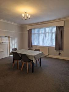 ein Esszimmer mit einem Tisch, Stühlen und einem Fenster in der Unterkunft Modern 3BD London Flat in London