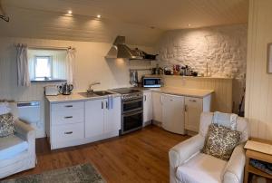 a kitchen with white cabinets and a stove top oven at The Ruah - Clifftop Retreat in Whitehall
