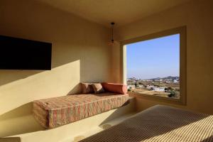 um quarto com um sofá e uma grande janela em Myconian Mythodea Luxury Villa em Ano Mera