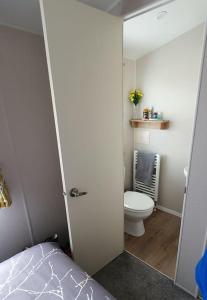 a bedroom with a bathroom with a toilet and a bed at Brookside West Sands Holiday Park Seal Bay Selsey in Selsey
