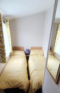 a small room with two beds and a mirror at Brookside West Sands Holiday Park Seal Bay Selsey in Selsey