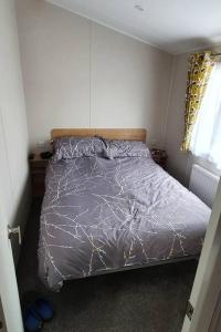 ein Schlafzimmer mit einem Bett mit einer lila Bettdecke in der Unterkunft Brookside West Sands Holiday Park Seal Bay Selsey in Selsey