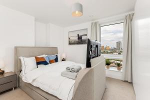 een slaapkamer met een bed, een televisie en een raam bij Khayat Homes - The Ferry - Two Bed in Londen