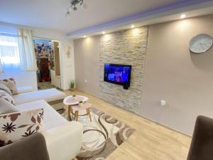 a living room with a tv on a stone wall at Apartman MiNa in Mataruška Banja