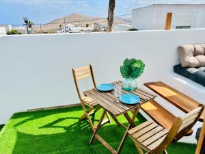 einen Tisch und Stühle auf einem Balkon mit grünem Gras in der Unterkunft LeS OiSeauX in Nazaret