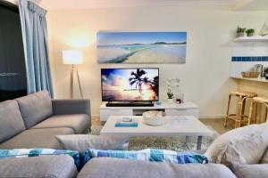 a living room with a couch and a tv at Poolside Retreat at Tropical Resort 126IP in Noosaville