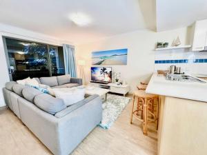 a living room with a couch and a kitchen at Poolside Retreat at Tropical Resort 126IP in Noosaville