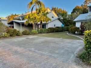 a driveway in front of a house with a palm tree at Poolside Retreat at Tropical Resort 126IP in Noosaville