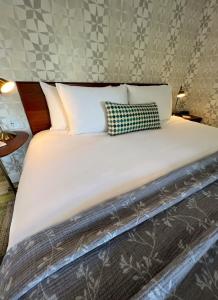 un grande letto con lenzuola e cuscini bianchi di Artisan Suites on Bowen a Bowen Island
