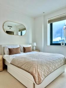 a white bedroom with a large bed and a mirror at Spacious Two Bedroom Apartment in London