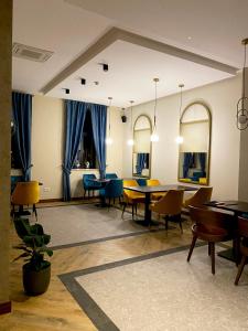 un comedor con mesas y sillas y cortinas azules en AVIOR Garni Hotel en Subotica