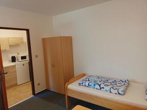 ein kleines Schlafzimmer mit einem Bett und einer Küche in der Unterkunft Apartmán Bokova chata in Nové Hutě