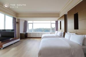 two beds in a hotel room with a large window at The South-Dawn in Hengchun