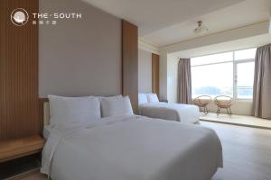 a hotel room with a large white bed and a window at The South-Dawn in Hengchun