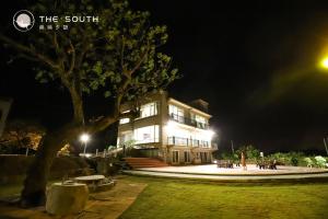 a large house at night with a tree in front at The South-Dawn in Hengchun