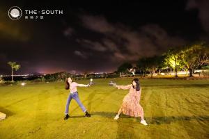 two women playing frisbee in a field at night at The South-Dawn in Hengchun