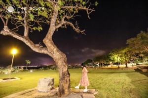 a woman in a dress standing next to a tree at The South-Dawn in Hengchun