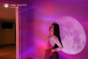 a woman standing in front of a purple wall with a moon at The South-Dawn in Hengchun